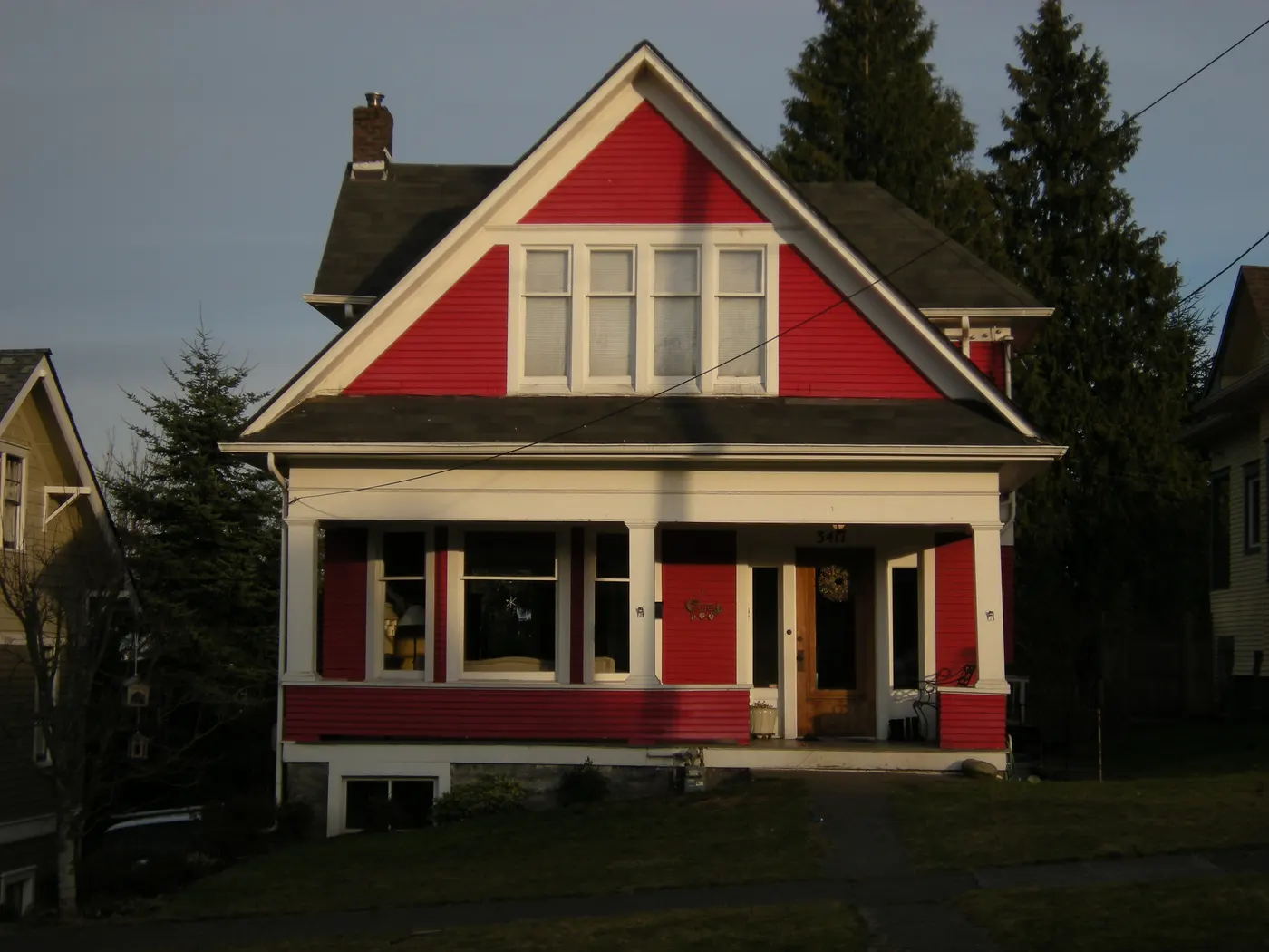 A red north Everett craftsman on Norton Avenue with a tall front gable, attic windows and evergreen trees beside the roofline