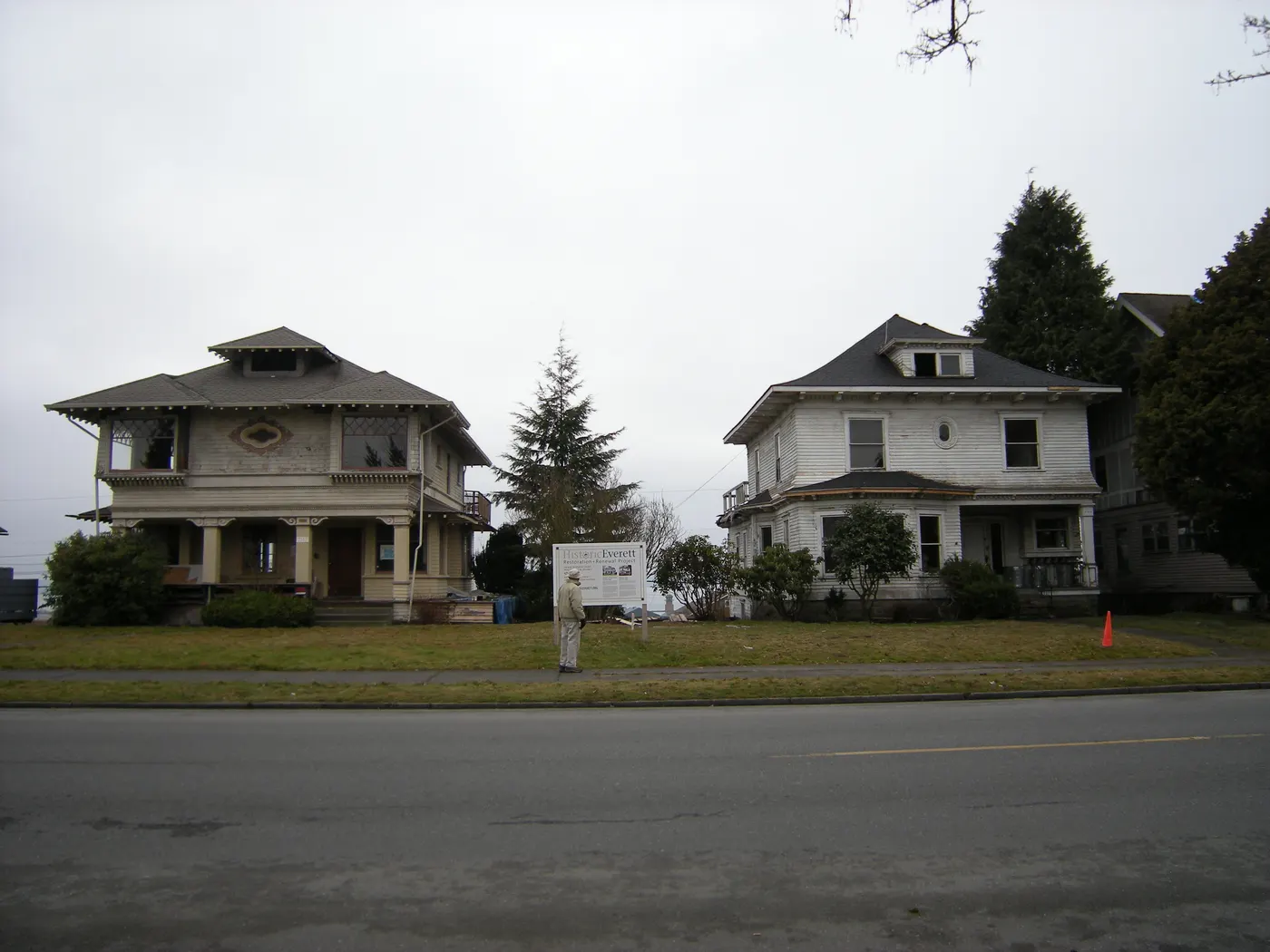 Two large early-1900s houses with deep front porches on Rucker Avenue in Everett, WA, with evergreen trees beside them