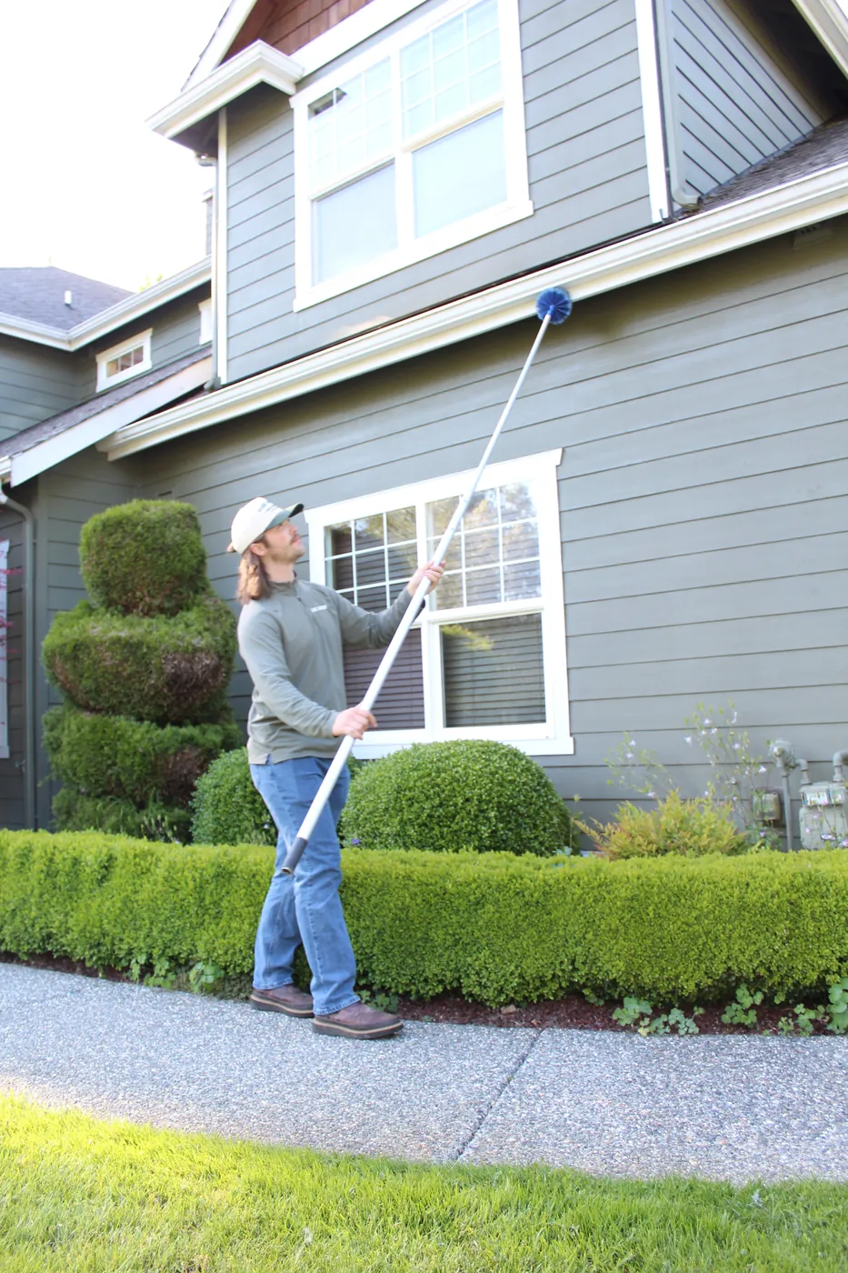 Pure Guard technician removing spider webs from a home's eaves during a spider treatment in Lake Stevens, WA